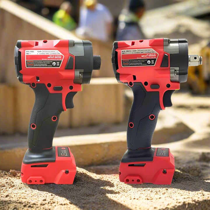 Two cordless red and black impact tools (a driver and a wrench) stand upright on a construction site with blurred workers and equipment in the background, showcasing their rugged durability and ergonomic grip.