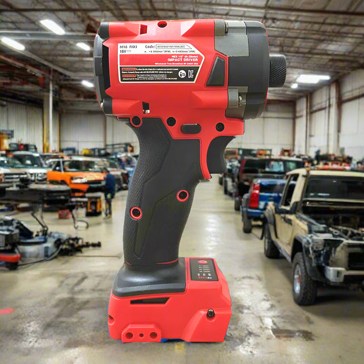 Red and black SmartGearPros cordless wrench standing in an auto garage with cars in the background.