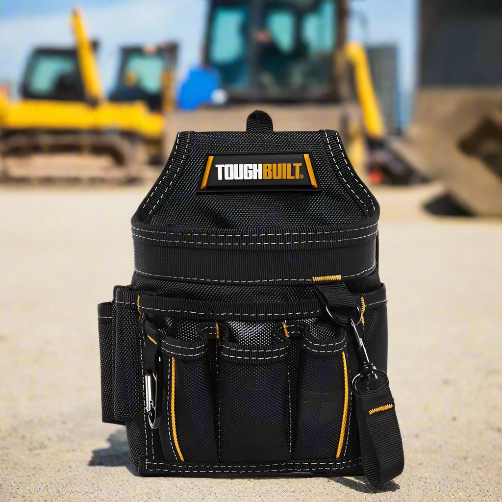 Durable black tool pouch with multiple compartments and rugged stitching, shown at a job site with construction vehicles in the background – perfect for tradespeople and professionals.