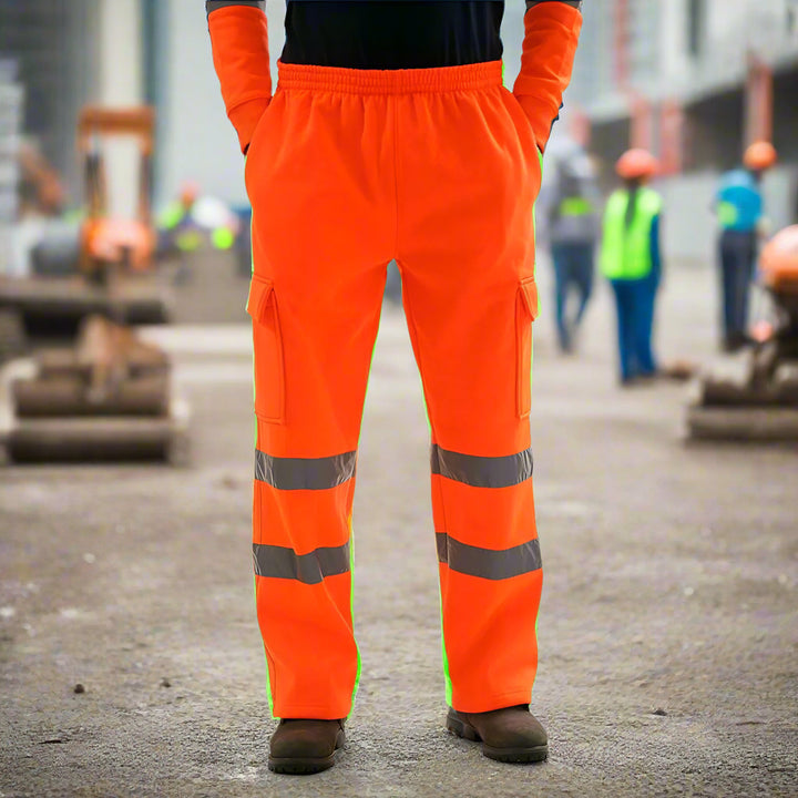 Bright yellow reflective safety pants showcased on a road at night with car headlights illuminating the background, emphasizing nighttime visibility.