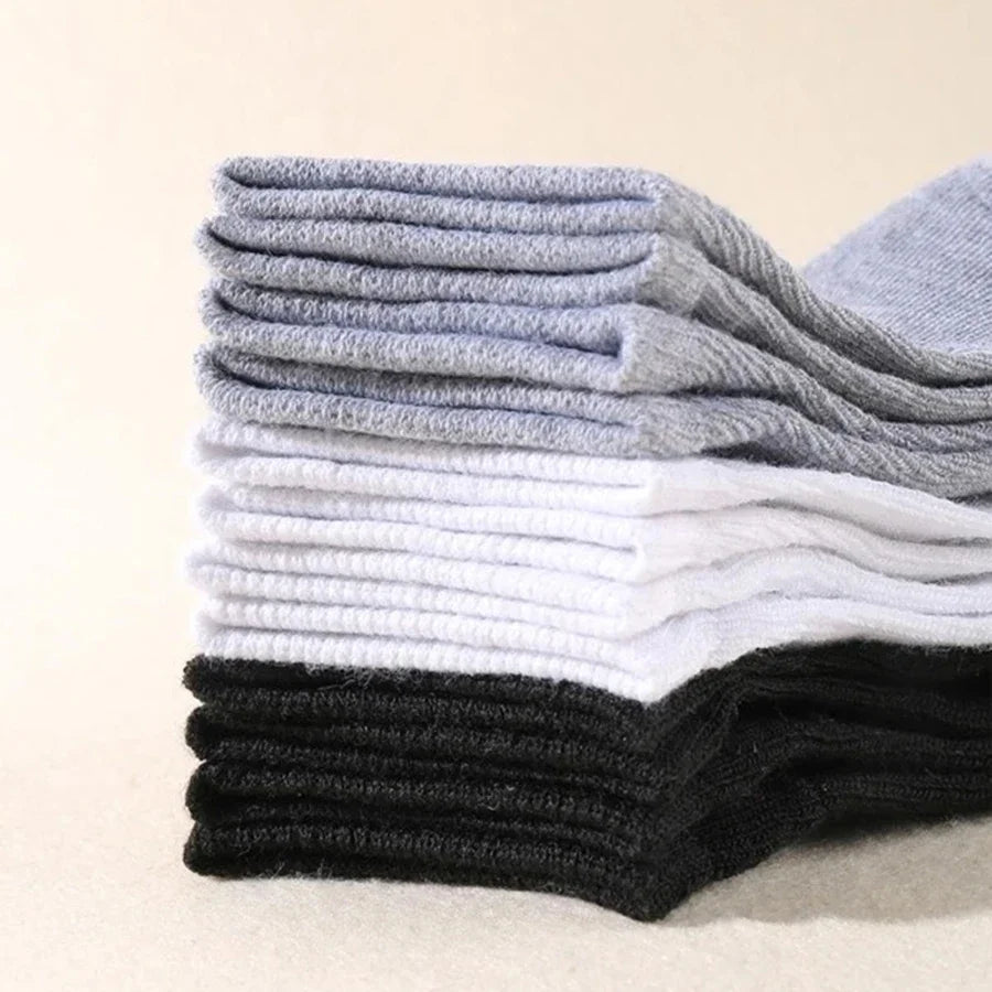 Neatly stacked black, grey, and white socks in a multipack arrangement.