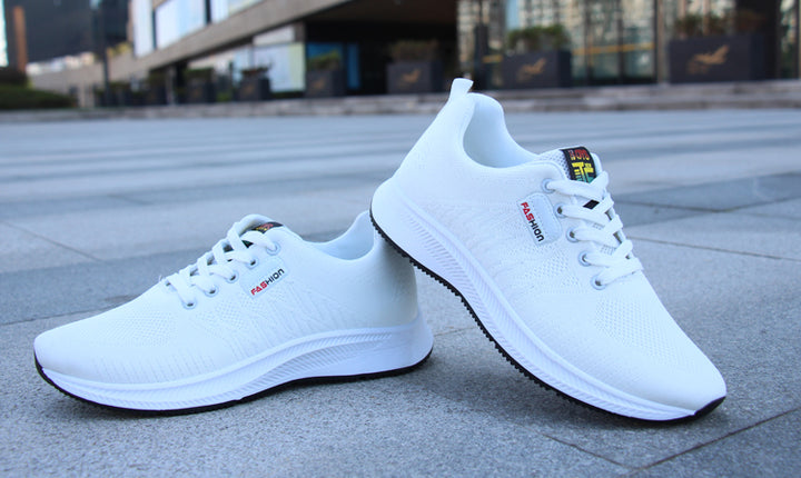 A clean pair of white sneakers positioned on an outdoor surface, perfect for sports, running, and casual fashion.