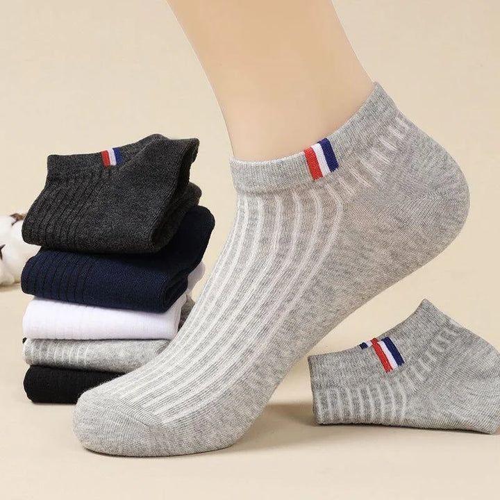  A close-up of a person wearing a grey breathable cotton ankle sock with a stylish stripe at the top.