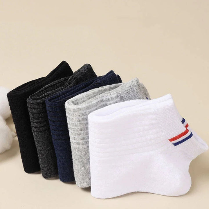 Neatly stacked black, white, grey, and navy socks, showing the soft and flexible fabric.